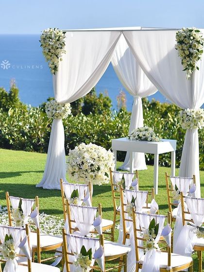 A pristine all-white wedding mandap set against a stunning ocean view. The clean lines and simple floral accents create a modern and sophisticated look.