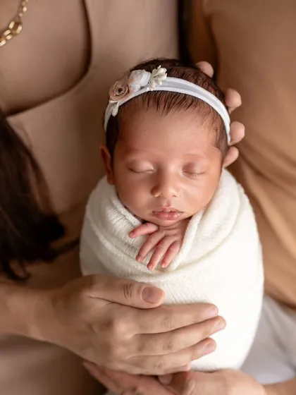A close-up of perfection. This swaddled newborn, held securely in loving hands, highlights their delicate features and the feeling of being cherished.