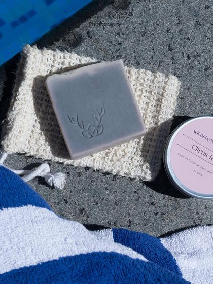 A simple, elegant shot of handmade soap and body butter by the pool. The natural sunlight and clean composition give this image a fresh and relaxing feel.