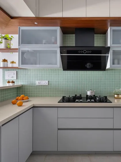 Another view of the 'Gulmohar' kitchen, showcasing the clean lines of the handleless cabinetry and the texture of the square tile backsplash.