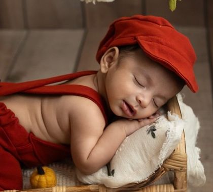 Dressed in a cozy red outfit and cap, this little one sleeps soundly. This portrait captures the warmth and comfort of the newborn phase, a perfect memory for a drizzly Bangalore day.