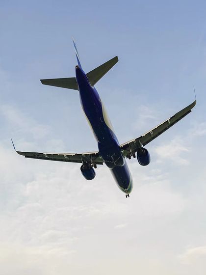 An airplane captured mid-flight from below, showcasing the power and design of the aircraft against the sky.