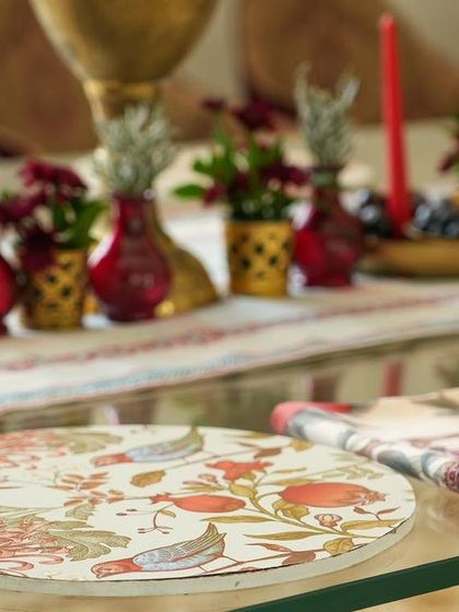 A custom-printed plate and napkin from the 'दाड़म ka Bageecha' theme, featuring beautiful illustrations of birds and pomegranates.