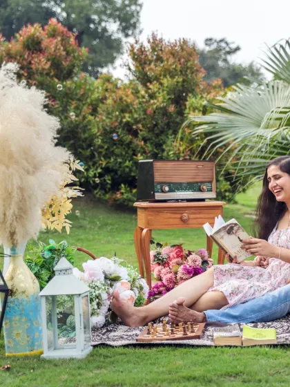 A beautifully styled picnic scene in a lush garden. This shot captures a relaxed and whimsical side of the couple's story, complete with vintage props, books, and flowers for a personalized touch.