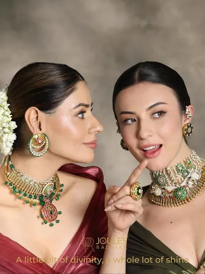 A little bit of divinity, a whole lot of shine. Two models showcase complementary layered looks, one with a grand choker and the other with a layered necklace, perfect for a bride and her sister.