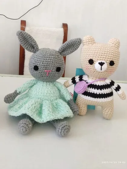A sweet pair of handmade friends, a grey bunny in a mint-green dress and a little bear in a striped shirt carrying a purse.