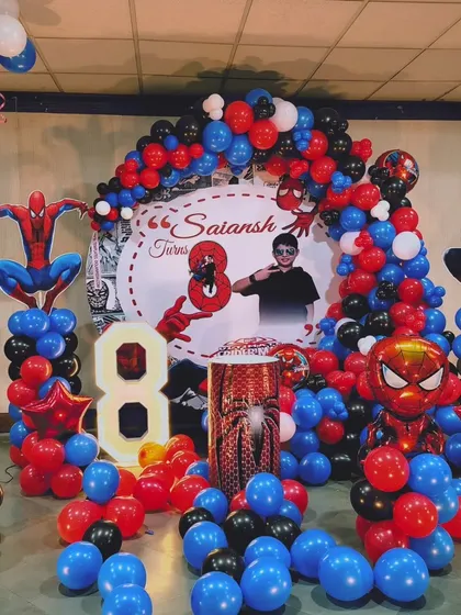 The main stage for the Spiderman party, featuring a personalized backdrop, character cutouts, a light-up number '8', and themed balloon columns.