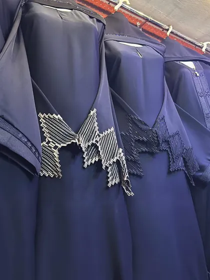 A row of navy blue abayas, each with a unique geometric beaded design on the chest. This shows how even within one colour, there are many styles to choose from.