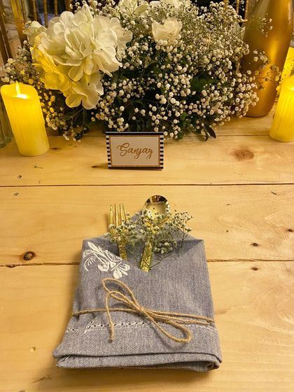 It's all in the details. For this sit-down dinner, each place setting featured custom-printed napkins, gold cutlery, and a small sprig of baby's breath for a cohesive and elegant look.