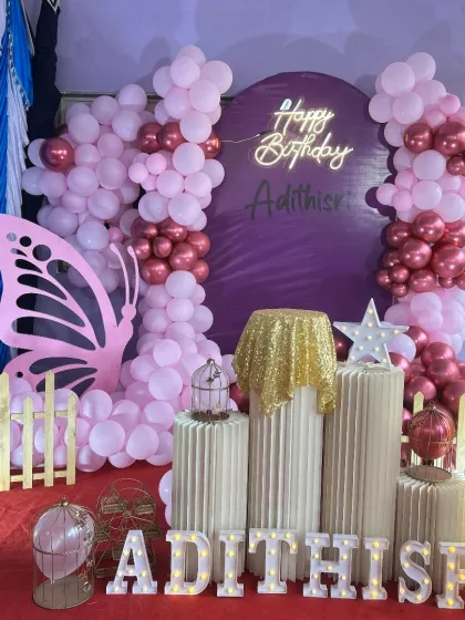 A butterfly-themed birthday with a dramatic flair. The purple backdrop is framed by a lush arrangement of pink and metallic rose gold balloons, with a large butterfly wing cutout and light-up number '11'.