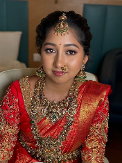 A happy, smiling portrait of Sowmiya. Her complete bridal look, from the flawless makeup to the traditional jewellery and red saree, is a perfect example of timeless elegance.