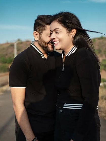 A sweet, candid moment with the wind gently blowing her hair. The natural, sun-drenched setting on a quiet road adds to the relaxed and intimate feel of this pre-wedding shot.