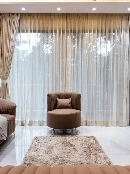 A view from the sofa in a modern living room, looking out through sheer curtains. The space is designed for comfort and relaxation, with a soft color palette and plush, contemporary furniture.