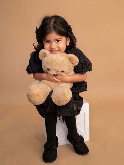 A sweet portrait of a big sister-to-be, hugging her teddy bear. This was part of a maternity session announcing a new baby on the way.