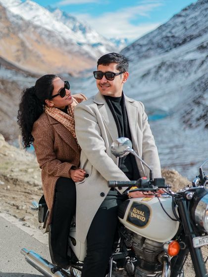 A stylish shot of a couple on a Royal Enfield, ready for an adventure on the mountain roads.