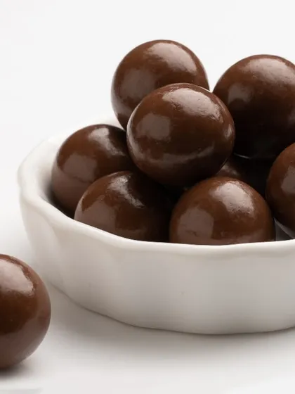 These are our chocolate coated hazelnuts, featuring a glossy dark chocolate shell over a whole roasted nut. They are a popular item in our coated nuts selection, known for their rich flavour and premium quality.