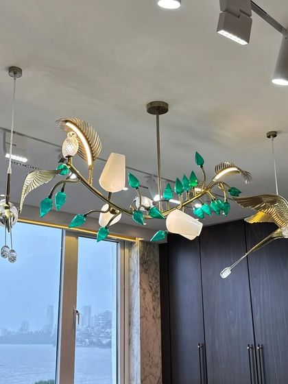 This close-up highlights the intricate details of the custom-designed chandelier, where golden birds appear to fly among glass leaves, creating a sense of movement and artistry.
