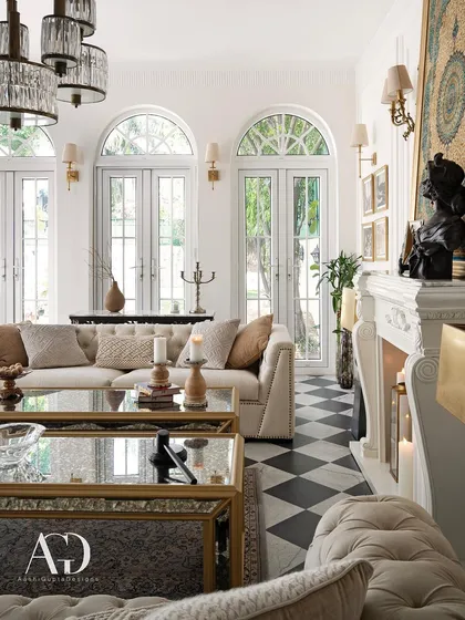 A bright and airy view of the French-inspired outhouse, focusing on the elegant fireplace and checkerboard floor. The design is a study in contrasts: black and white, classic and modern, formal and relaxed.