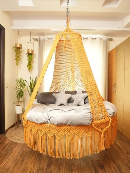 A sunny yellow macrame swing that brightens up this bedroom. The star-shaped pillows add a playful touch, making it a cheerful and inviting spot.