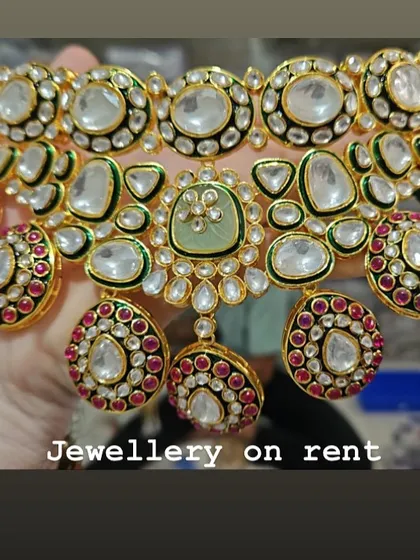 A close-up of the multi-colored meenakari kundan choker, held in hand to show the detail. This piece is available on rent.