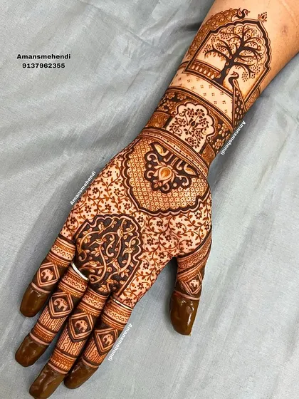 An intricate design with a peacock perched by a tree in a jharokha on the wrist. The palm is filled with delicate floral and paisley patterns.