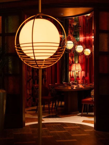 Looking into our private dining space from the main bar area. The view through the doorway hints at the exclusive experience within, framed by our signature spherical lighting.