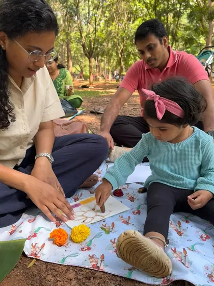 A mother and father sit with their daughter, fully engaged in a creative activity on a beautiful day in the park. It is these simple, shared experiences that I aim to create for families.