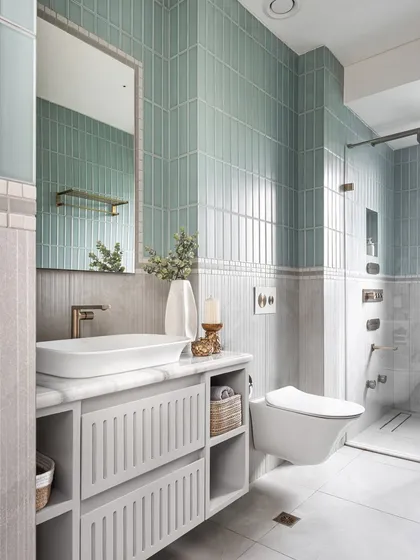 This en-suite bathroom continues the harmonious color story from the bedroom. We used a half-and-half wall treatment with sleek fluted grey tiles on the bottom and striking green subway tiles on top, divided by a bespoke mosaic border for an artistic touch.
