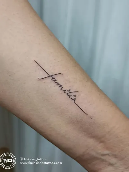 A clean, crisp, single-line script tattoo of the word "Familia." This elegant design is a timeless tribute to the importance of family.