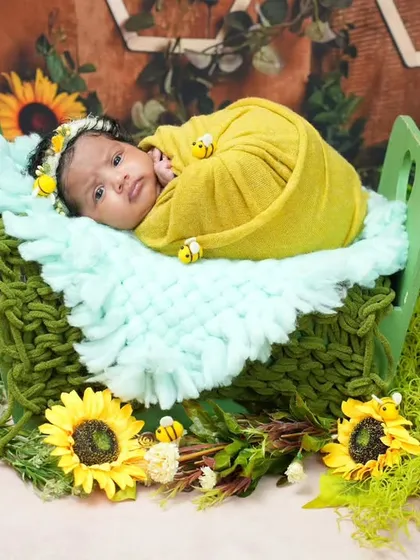 A closer look at our bee-themed newborn shoot. The baby is wrapped in yellow and surrounded by sunflowers, looking peaceful and sweet.