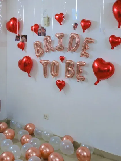 A wider angle of the room, showing the 'BRIDE TO BE' banner and balloons scattered on the floor.