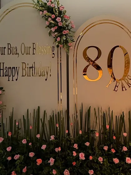 Celebrating a life rich with memories requires decor to match. For this special 80th birthday, we created a personalized backdrop with elegant gold lettering and a garden of fresh pink roses, crafting a space that felt both grand and deeply personal.