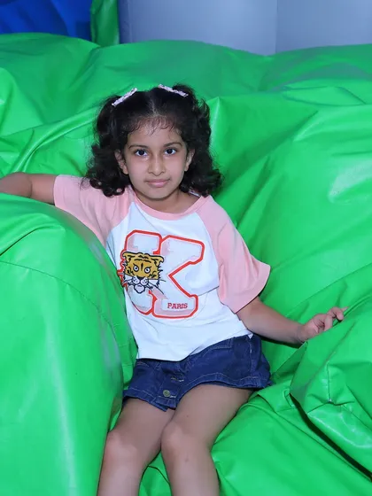 A young girl relaxes inside one of our bouncy green inflatables. These structures provide a safe and fun environment for kids to climb and play.