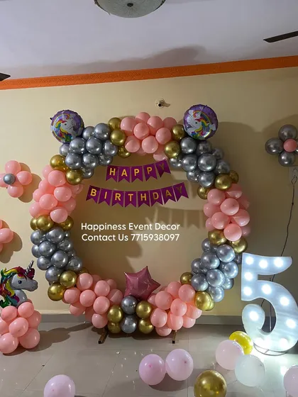 A unicorn-themed balloon ring decoration for a 5th birthday, complete with a light-up marquee number.
