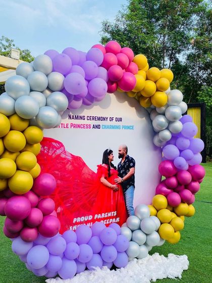 A closer look at the custom naming ceremony backdrop, showing the vibrant pink, yellow, purple, and silver balloons.