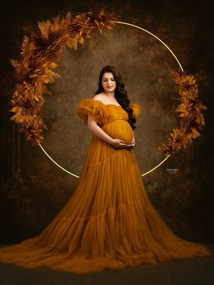 A beautiful composition featuring a mustard tulle gown and a rustic, illuminated floral hoop. The dark, textured background makes the warm colors of the setup truly shine.