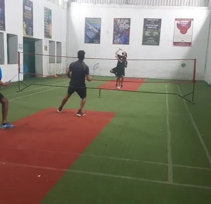 A female player leaps for an overhead smash while her partner covers the front court. Great teamwork!