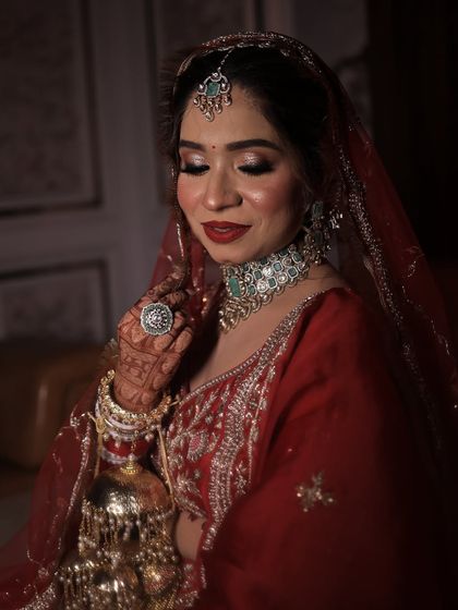 A soft, romantic pose showing the side profile and the intricate details of her jewellery and makeup. The red tones create a warm and inviting feel.
