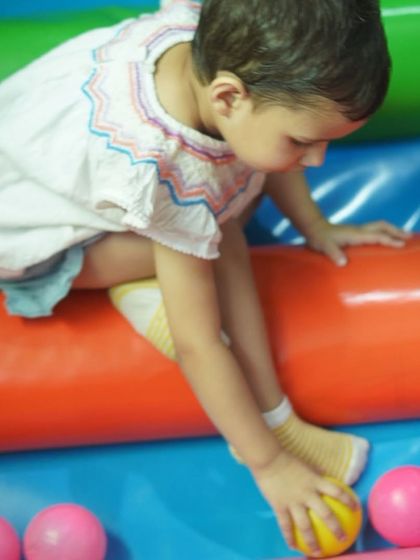 A toddler carefully choosing a ball, engaged in sensory play in a safe and soft environment.