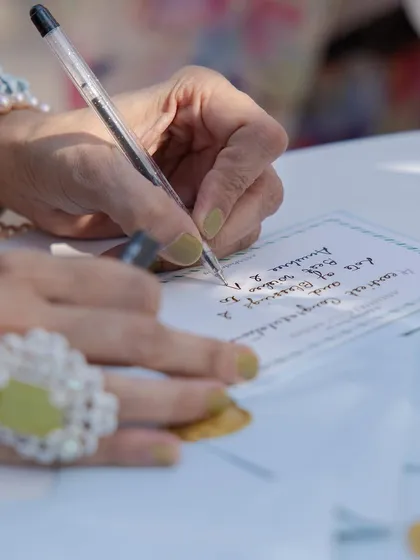 A guest pens a heartfelt note for the couple. We design these experiences to be as beautiful as they are meaningful, with elegant stationery and a comfortable setting.