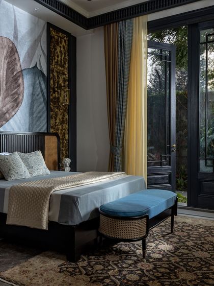In this bedroom, a large doorway opens directly to the garden, blurring the boundary between the interior and the natural world. We used a mix of textures, including cane and rich fabrics, to create a space that feels both sophisticated and serene.