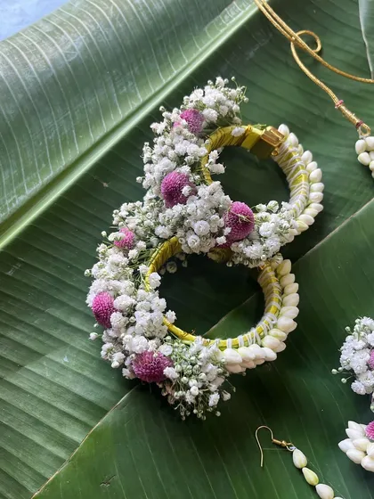 A close-up of the floral bracelets from the jasmine bud set. The design is built on a sturdy base and decorated with baby's breath and pink flowers.