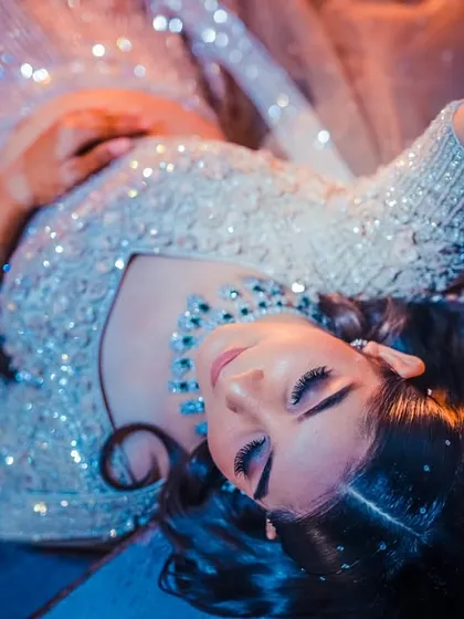 An overhead shot of a bride lying down, her glittering dress fanned out around her, creating a stunning, artistic portrait.