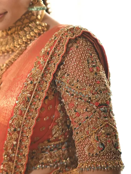 A detailed view of a heavily embroidered blouse sleeve. The combination of beadwork, sequins, and Zari creates a rich, three dimensional texture that is pure luxury.