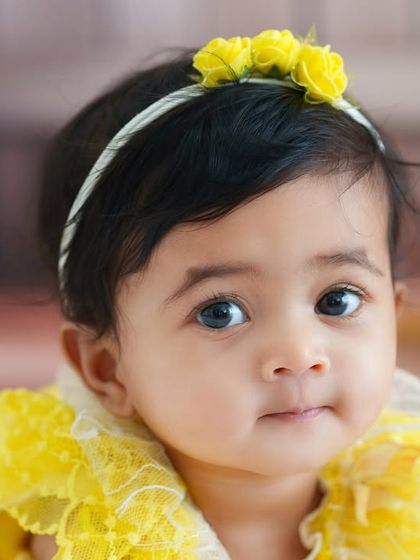 A sweet and simple close-up portrait of a baby girl. The soft, out-of-focus background and the yellow floral headband draw all the attention to her beautiful eyes.