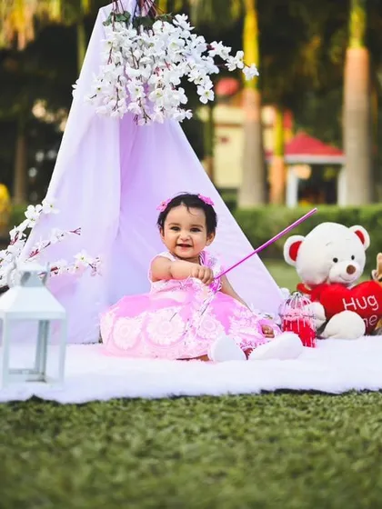 The birthday girl enjoying her pink-themed outdoor setup. The props are placed within her reach to encourage interaction and capture natural smiles.