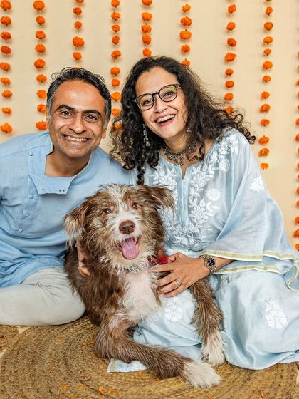 A happy family portrait from a Rakshabandhan mini-shoot. The couple smiles warmly with their scruffy, adorable dog, celebrating the festive occasion together.