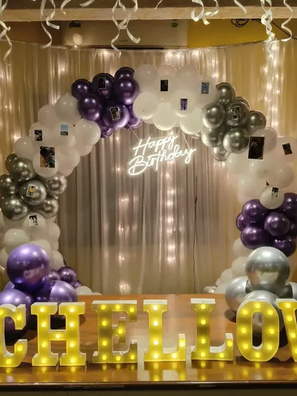 A closer look at the personalized table-top balloon arch. You can see the small photos hanging from the balloons, adding a unique and sentimental touch to the birthday decor.