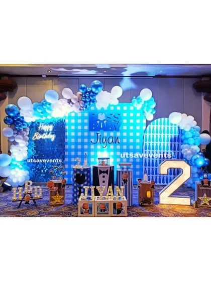 A fun and stylish 'Boss Baby' themed birthday party. This setup includes character cutouts, a blue sequin backdrop, and a large light-up number '2', perfect for a little one's celebration.