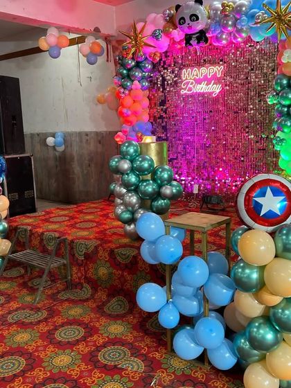 A superhero and panda themed party with a pink sequin wall, a Captain America shield, and a multi-colored balloon arrangement.